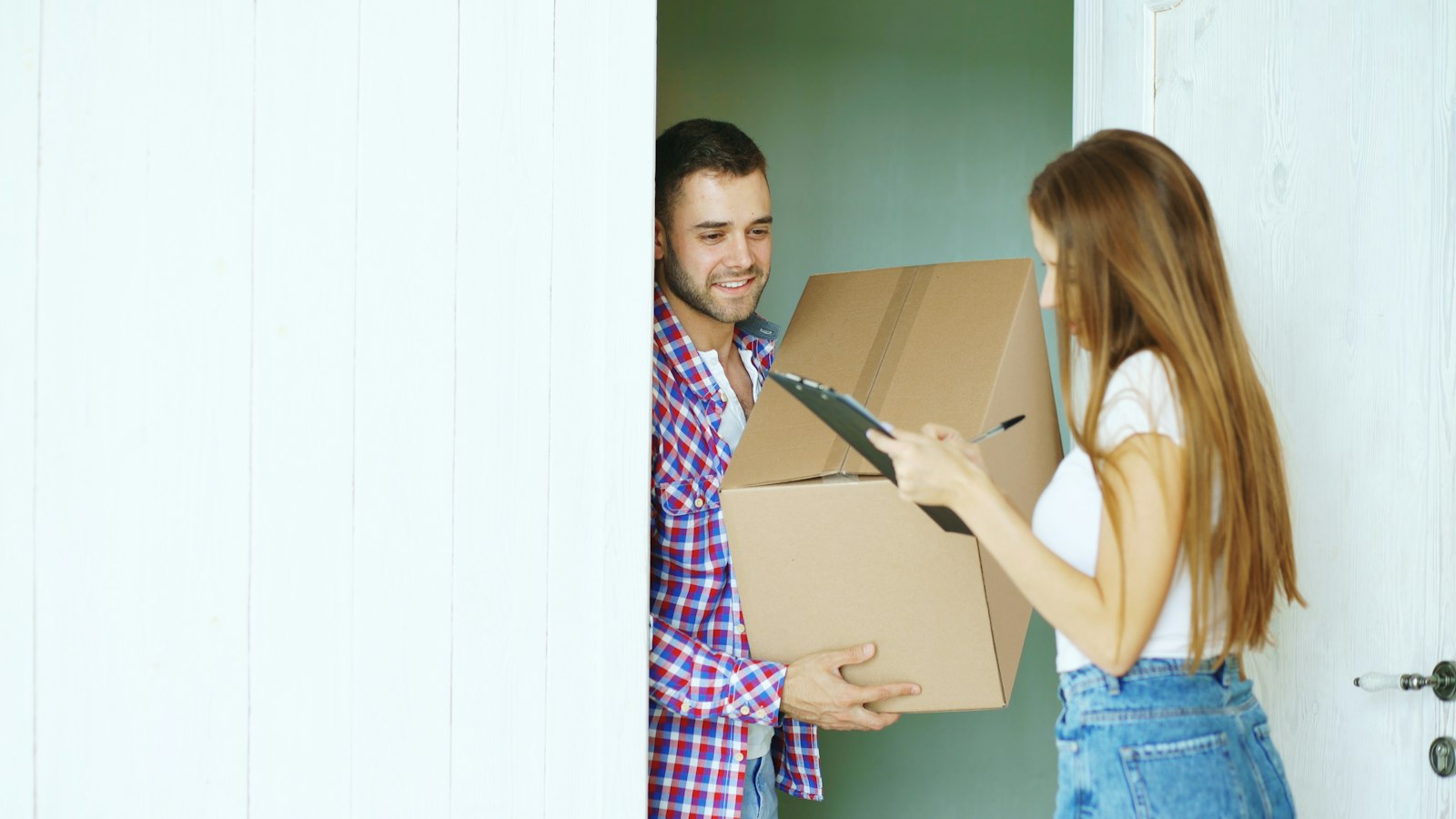 A couple receiving a cardboard parcel at their front door
